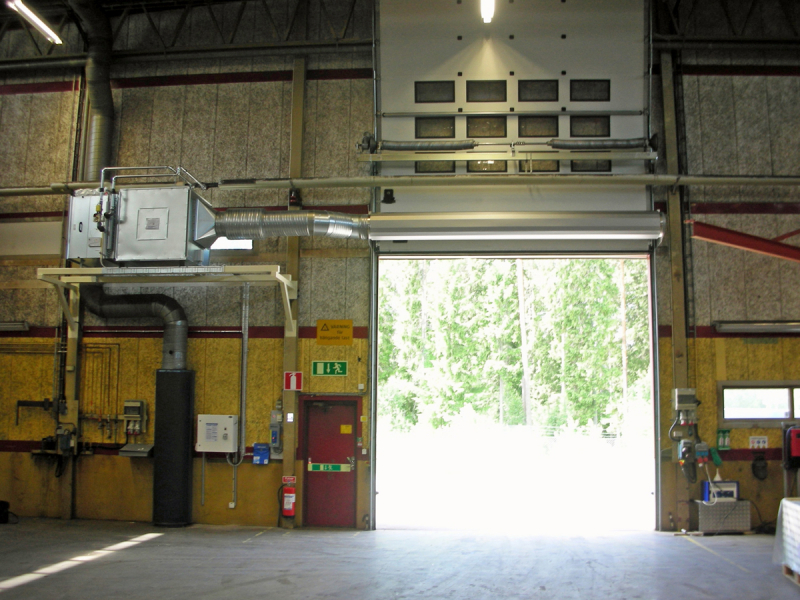 En ovanblåsande luftridå från RMK på industriport med gul vägg.