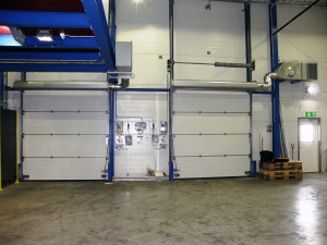 Ovanblåsande luftridåer från RMK på industriport med blå stålram.