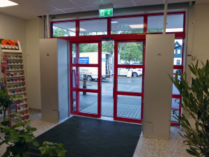 Sidoblåsande luftridåer från RMK i en entré med röda dörrar.
