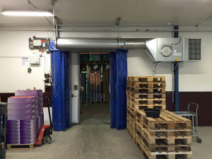 Ovanblåsande luftridå från RMK på en frys med blåa gardiner.