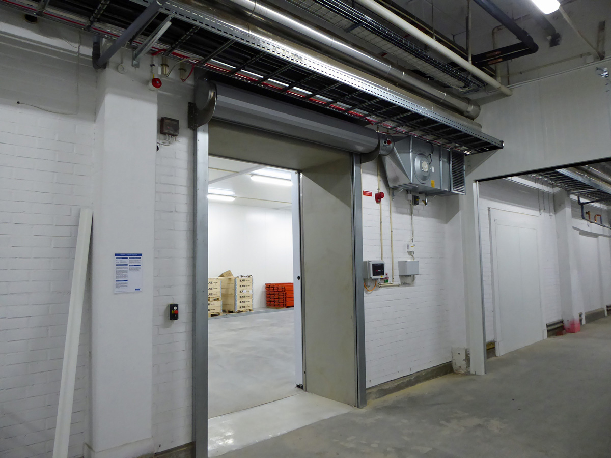 Ovanblåsande luftridå från RMK på en frys med vita väggar.