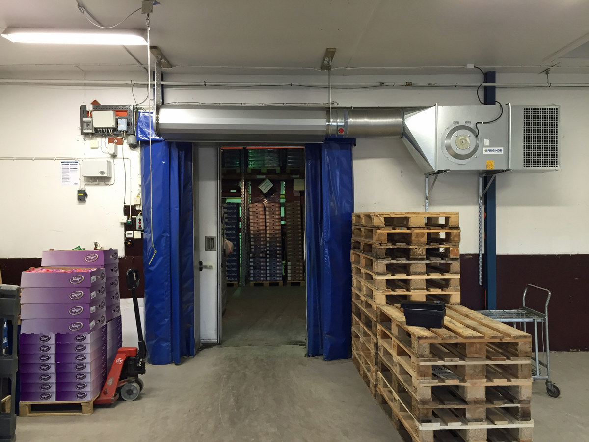 Ovanblåsande luftridå från RMK på en frys med blåa gardiner.