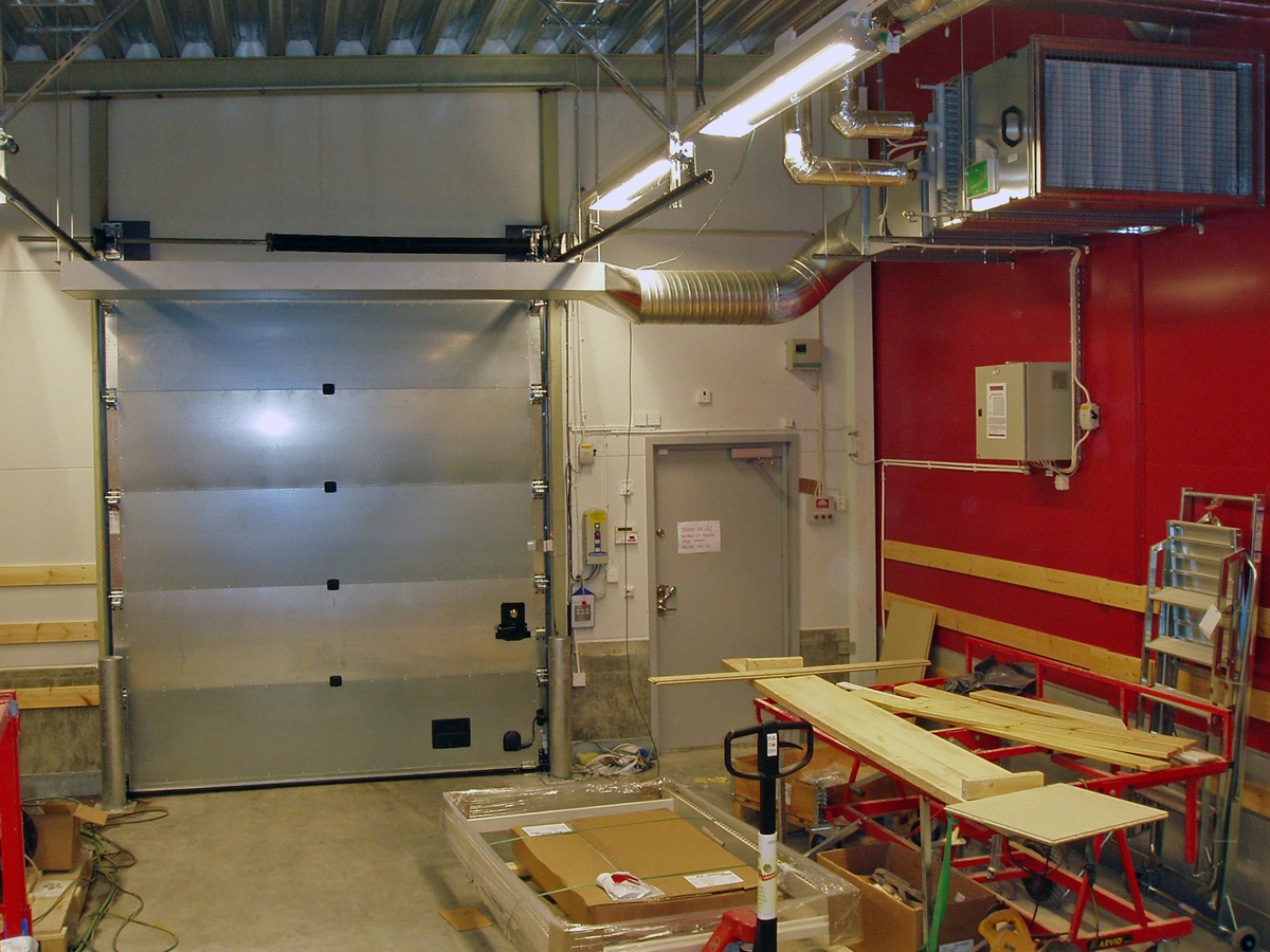 En ovanblåsande luftridå från RMK på industriport med röd vägg.