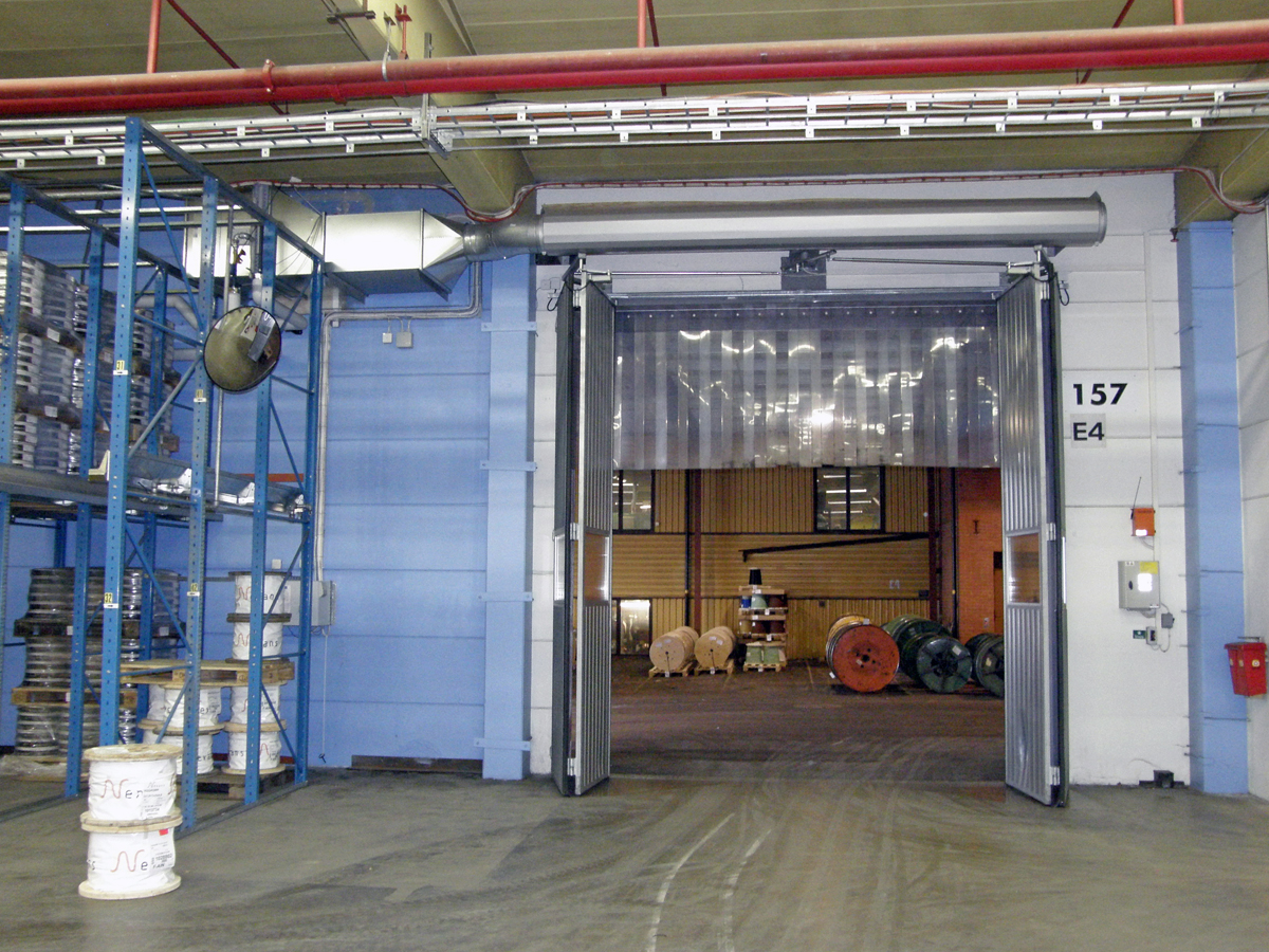 En ovanblåsande luftridå från RMK på industriport med blå vägg.