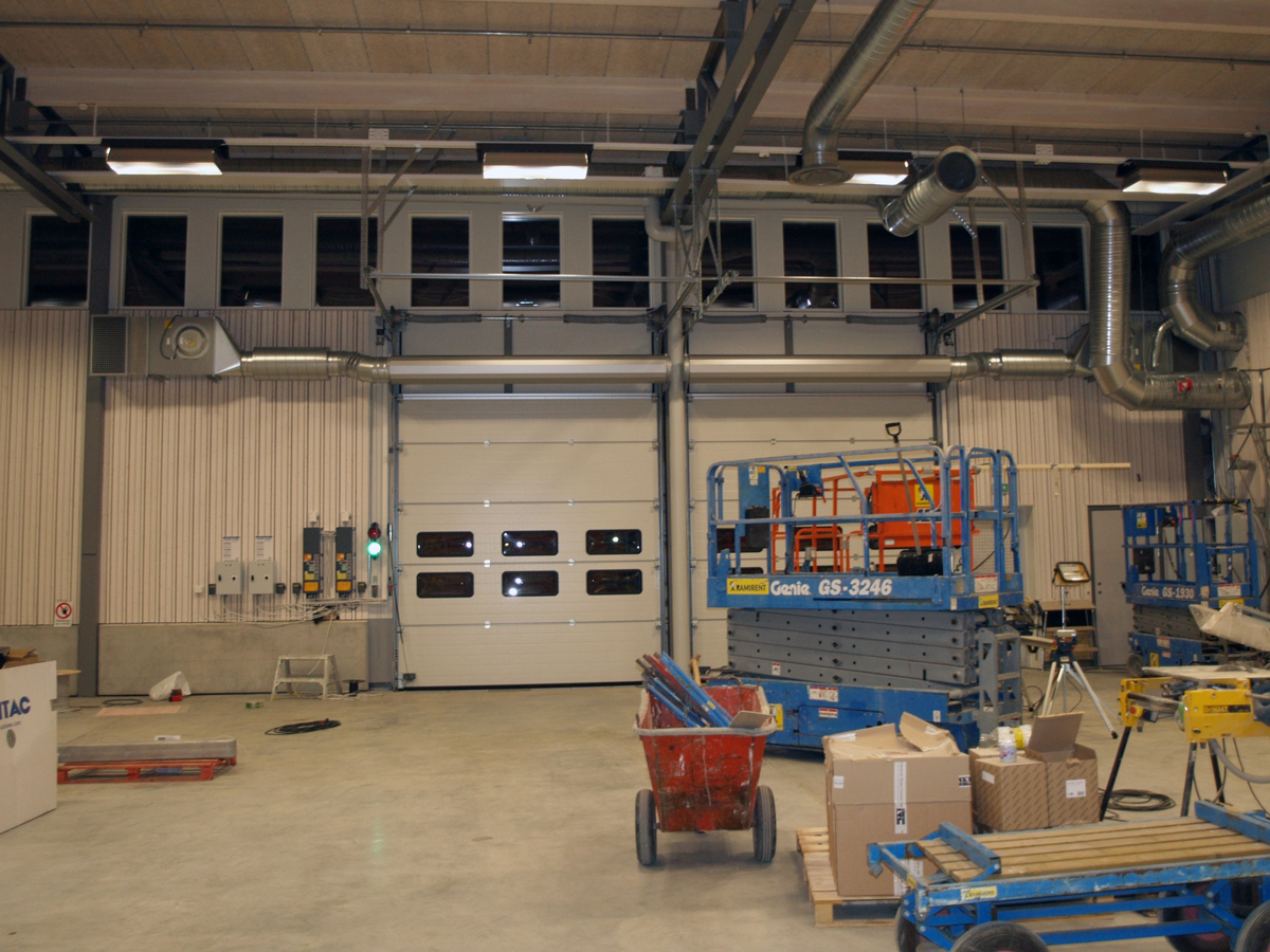 Ovanblåsande luftridåer från RMK på industriport med blå saxliftar framför.