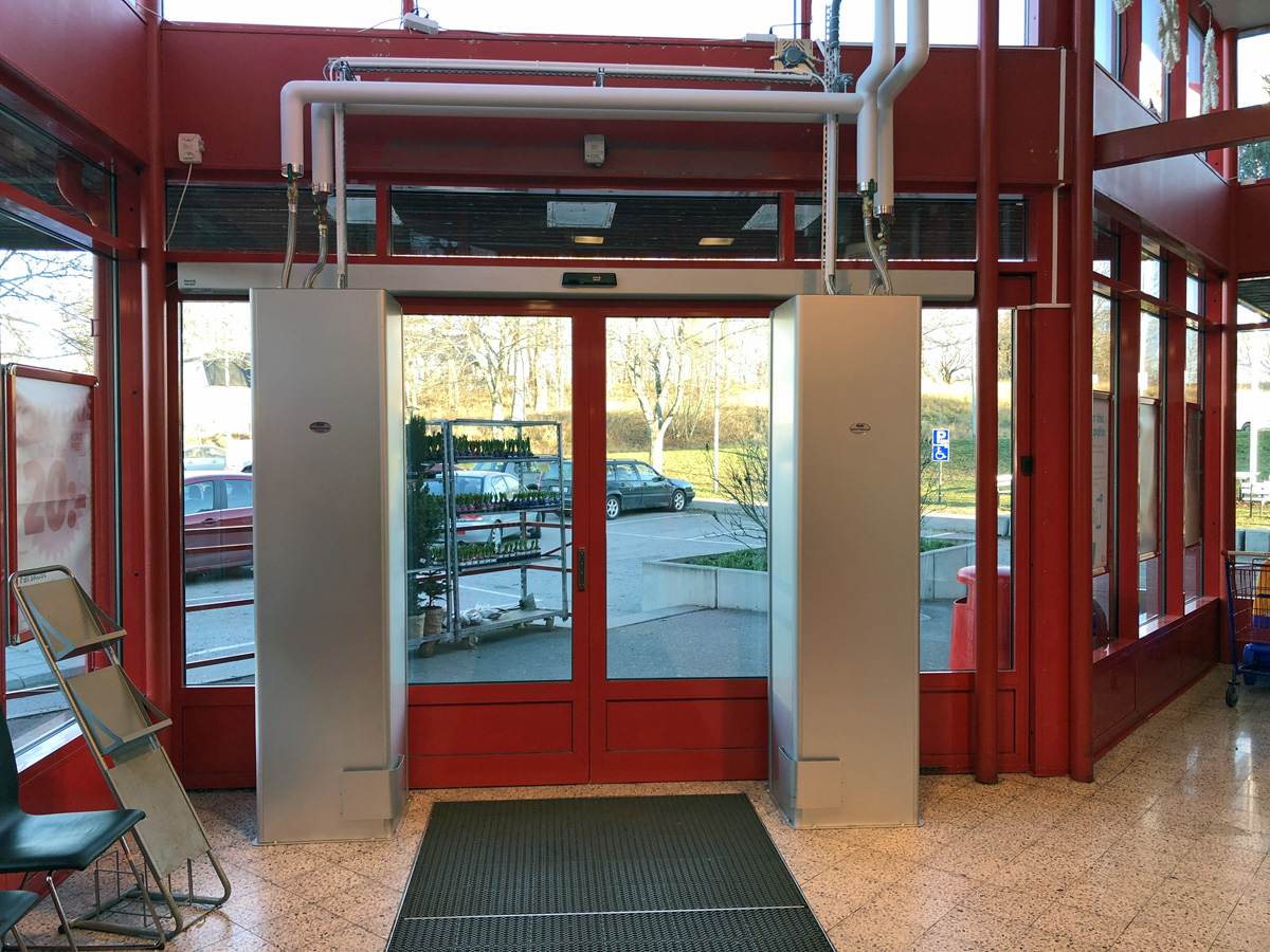 Sidoblåsande luftridåer från RMK i en entré med röda dörrar.